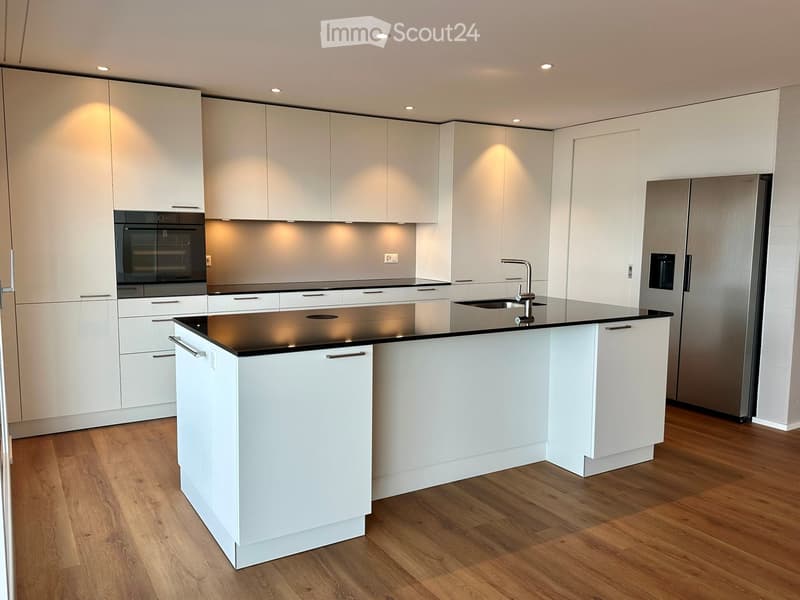 modern kitchen with white cabinets, black countertops, stainless steel refrigerator, dishwasher, oven, island with sink and faucet