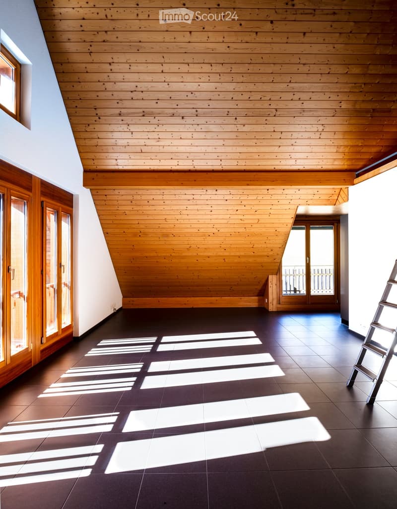 Empty room with wooden ceiling, dark tiled floor, large windows, and wooden doors.