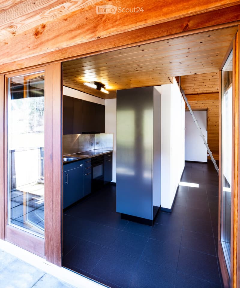 Modern kitchen with dark blue cabinets, stainless steel appliances, and a sleek black tiled floor.
