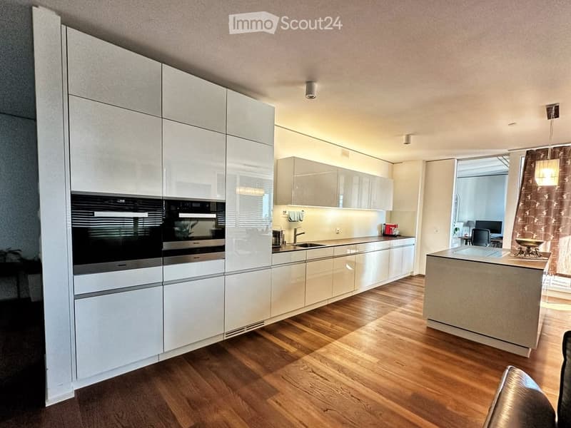 Modern kitchen with white cabinetry, stainless steel appliances, wooden flooring, and an island with seating.