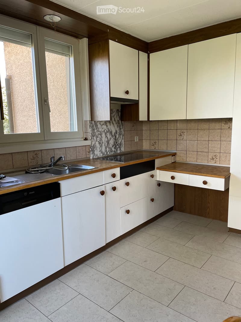 Modern kitchen with white cabinets, wooden countertops, a sink, and a dishwasher. The backsplash features a marble design, and the floor is tiled.
