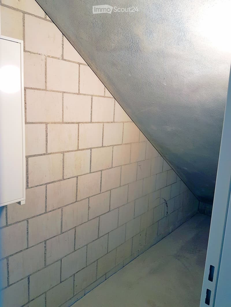 corner of a room with white tiled wall, slanted ceiling
