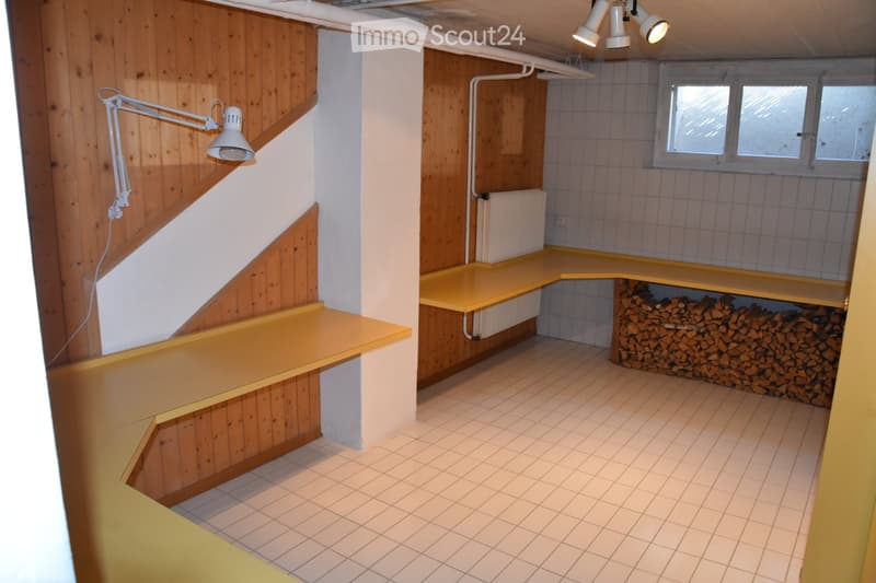 Empty room with wooden walls, tiled floor, built-in yellow shelves, and a stack of firewood in the corner. No furniture or equipment present.
