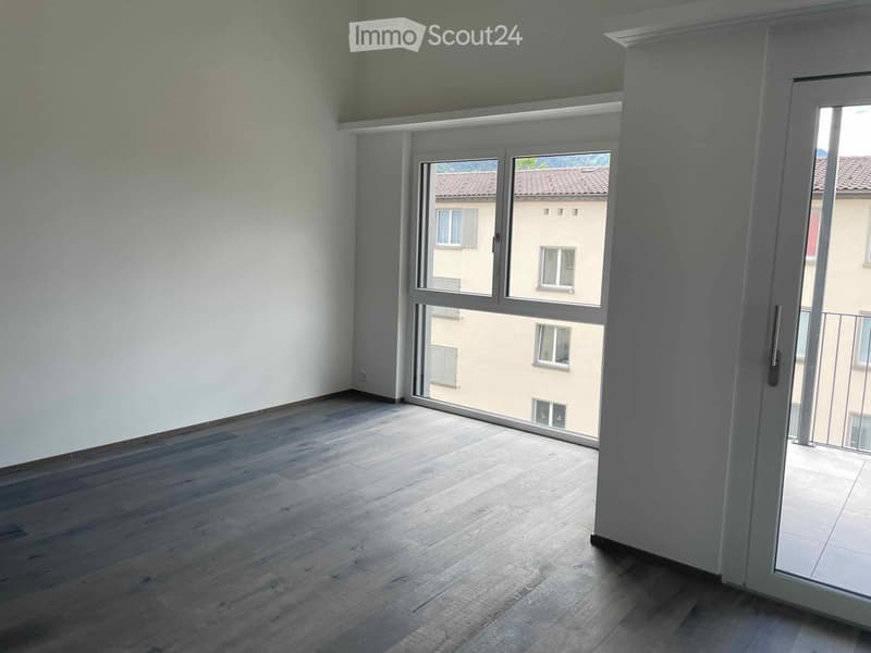 Empty room with wooden flooring, large windows, and white walls. No furniture or equipment present.