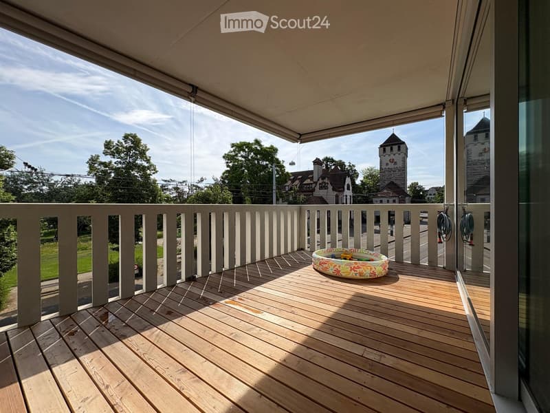 Wooden balcony with railing, retractable awning, and a small inflatable swimming pool.