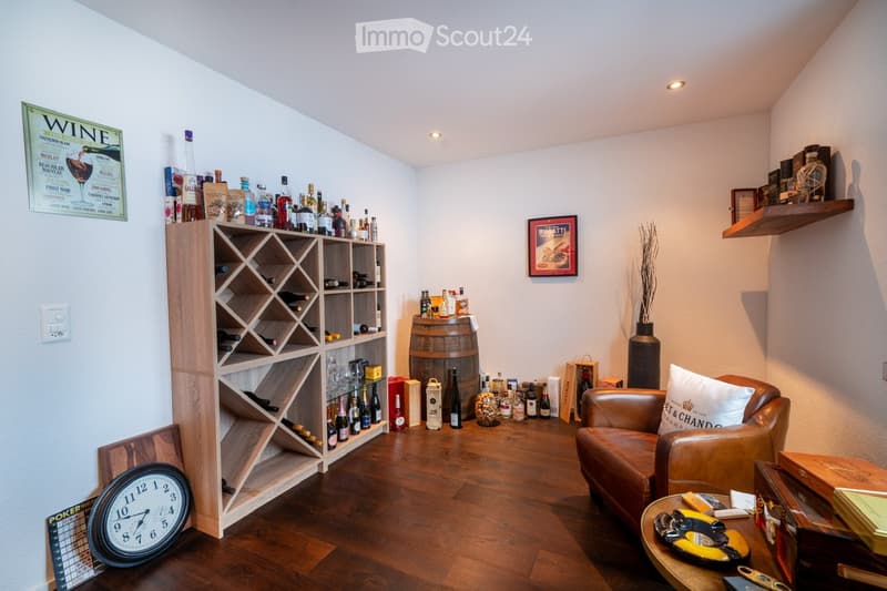 wine storage room with bottles, a chair, a wooden shelf, a desk with items, a poster on the wall