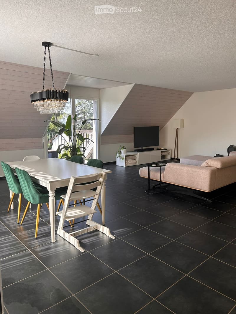 Modern living and dining area with a white dining table, green chairs, a beige sofa, a television, and a chandelier.