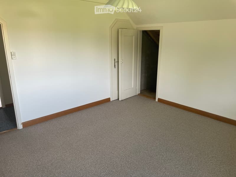 Empty room with light-colored walls, carpeted floor, and a single white door leading to another area.