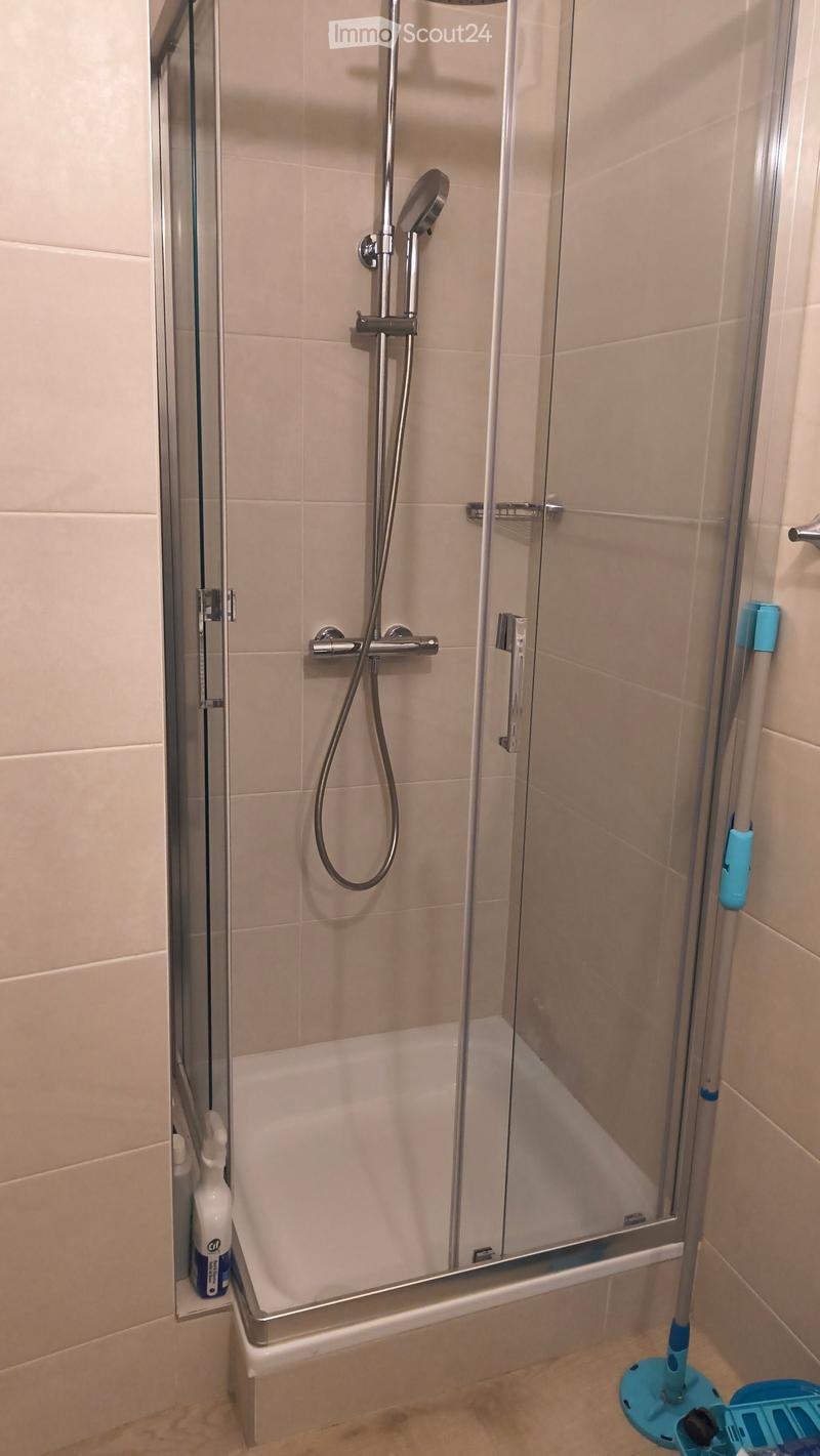 Modern bathroom with a bathtub, glass-enclosed shower, and tiled walls.