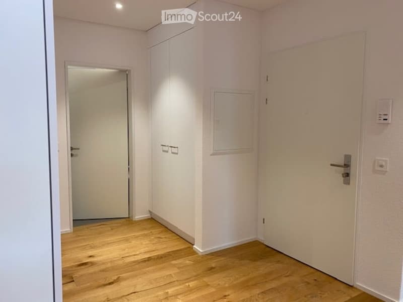 Empty room with light wooden flooring, white walls, and two white doors. No furniture or equipment present.