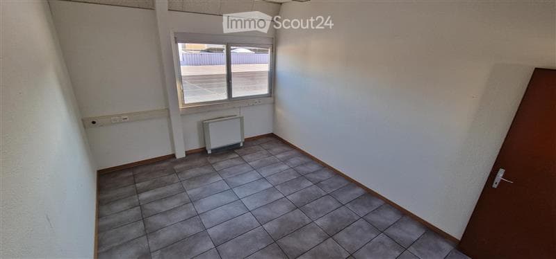 Empty room with tiled floor, white walls, a single window, and a radiator. No furniture or equipment present.