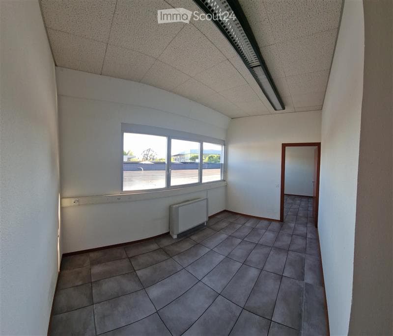 Empty room with tiled floor, white walls, large windows, radiator, and a door leading to another space.