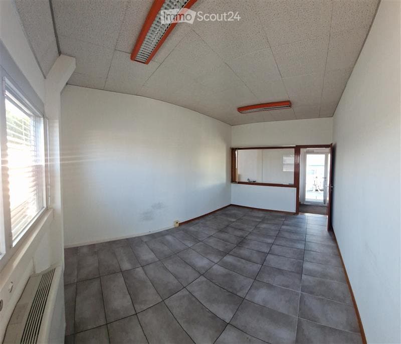 Empty room with tiled floor, white walls, and a large window with blinds. There is a door leading to another space.