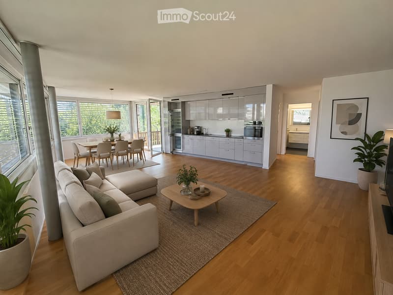 Modern open-plan living and dining area with light wood flooring, large windows, a sectional sofa, coffee table, dining table with chairs, and a sleek kitchen with white cabinets and stainless steel appliances.