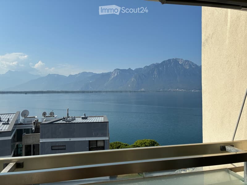 Balcony overlooking a large lake with distant mountains in the background.