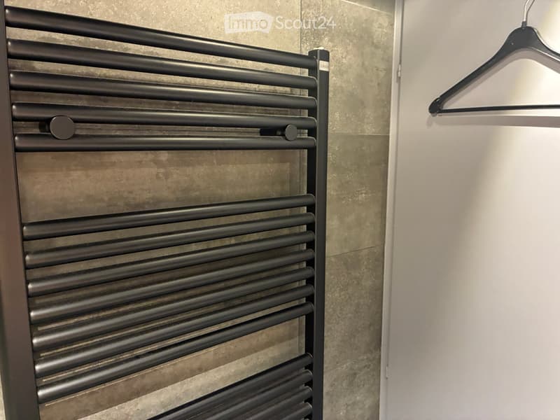 Bathroom with a modern black radiator and a white wall-mounted hanger.