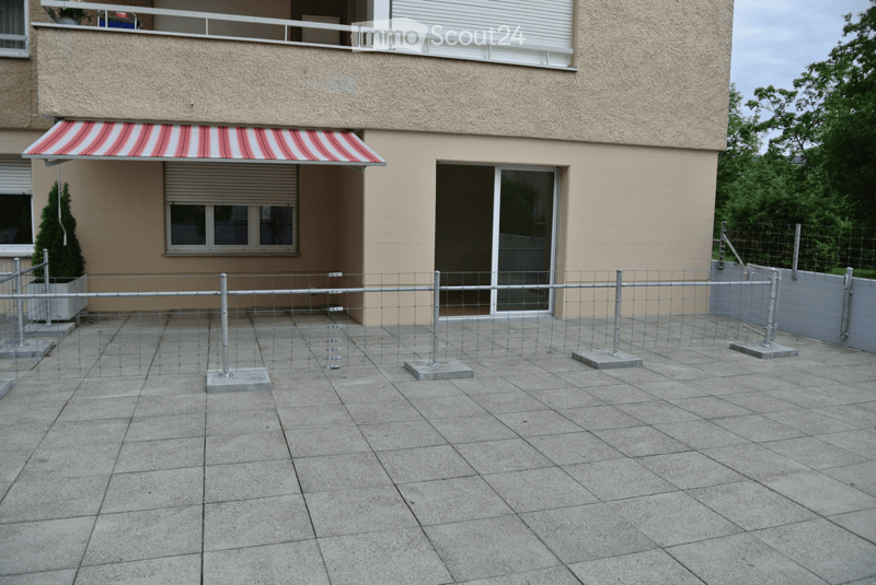 Balcony with tiled floor, metal fence, and awning attached to a building.