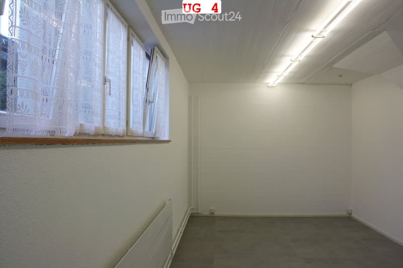 Empty room with white walls, tiled floor, and large windows with lace curtains. No furniture or equipment present.