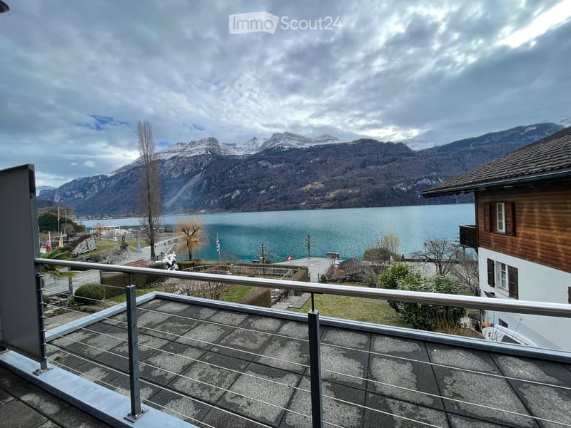 Balcony with a view of a lake and snow-capped mountains in the background.