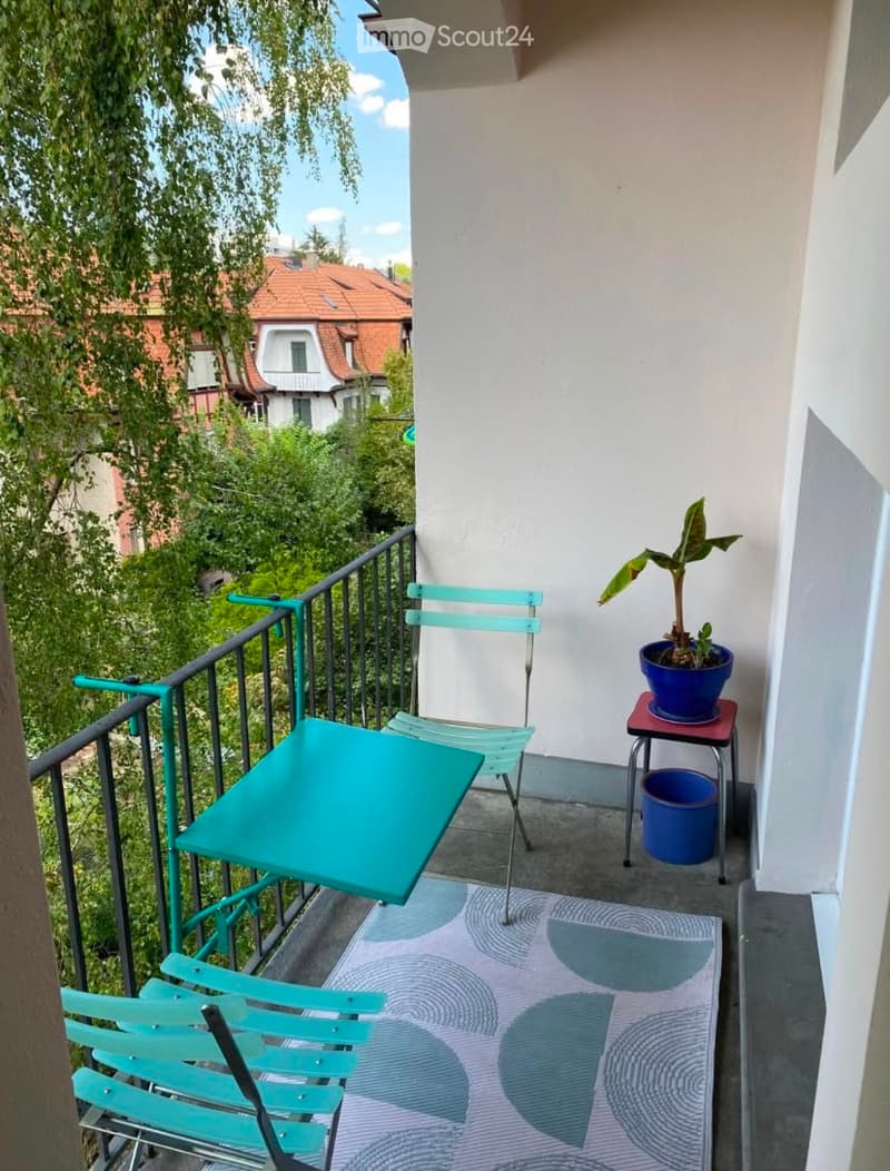 Balcony with a small table, chairs, a potted plant, and a rug.
