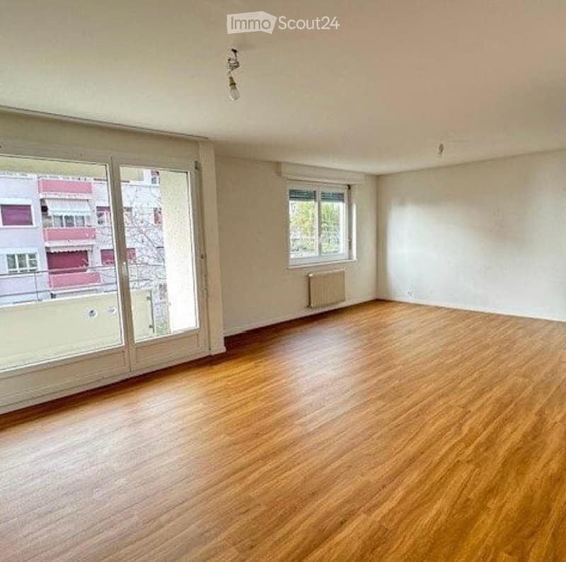 Empty room with wooden flooring, large glass sliding doors, and a radiator. No furniture or equipment present.