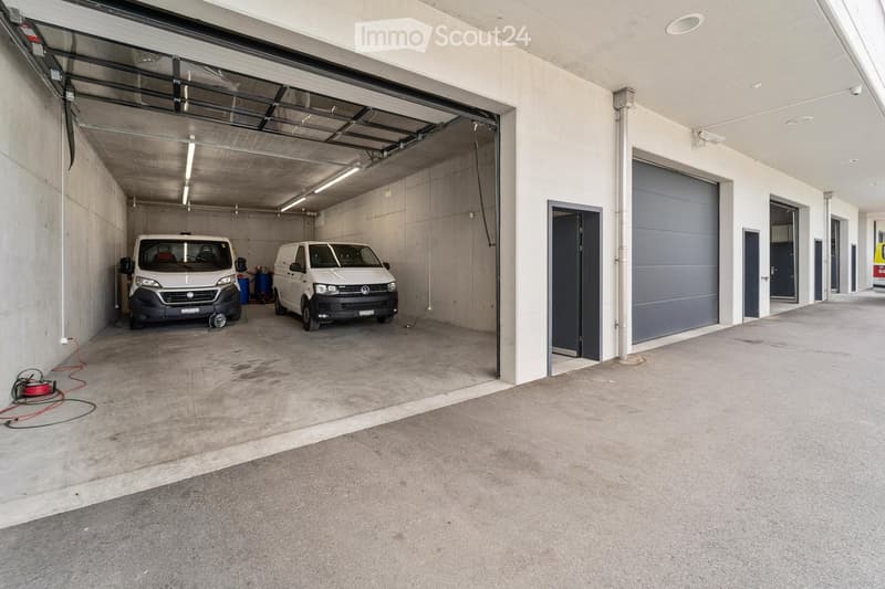 Underground garage with two parked vans, concrete walls, and a large open space.
