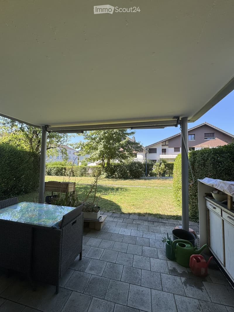 Patio area with tiled floor, outdoor table and chairs, potted plants, and gardening tools.