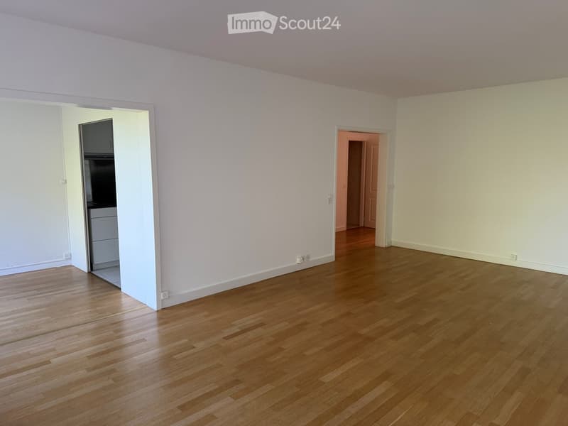 Empty room with light-colored walls and wooden flooring, featuring two open doorways leading to adjacent spaces.
