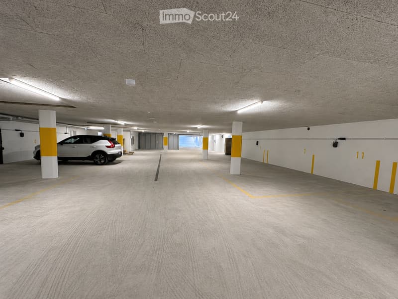 Modern underground parking area with clean, organized space, marked parking spots, and a single parked car.