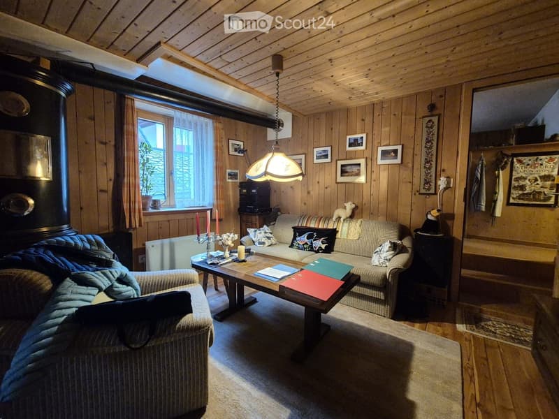 Cozy living room with wooden walls and ceiling, featuring a sofa, coffee table, fireplace, and decorative items.