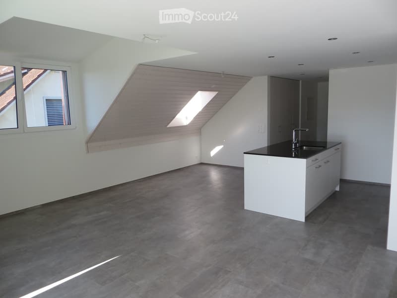 Modern kitchen with white cabinets, black countertop, and a sink. The space features wooden slatted walls and large windows allowing natural light to fill the room.