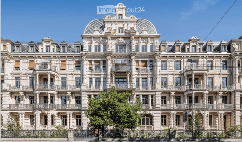 Ornate multi-story building with classical architecture, numerous windows, balconies, and decorative stonework.