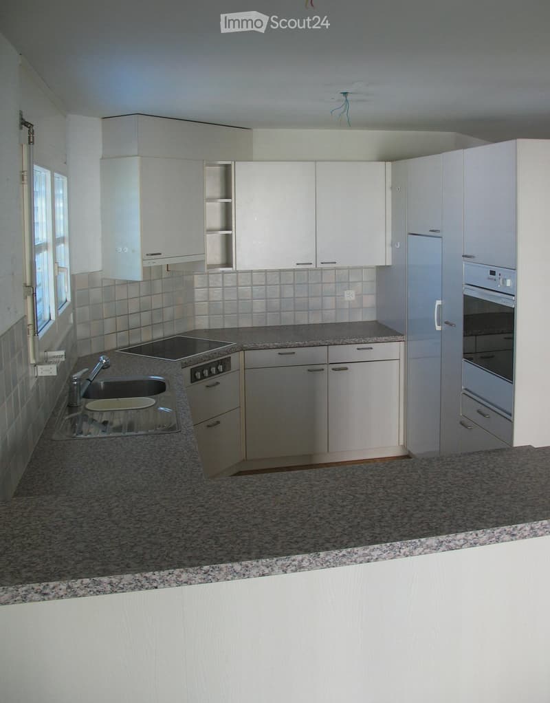Modern kitchen with white cabinets, granite countertops, stainless steel sink, and built-in appliances including an oven and stove.