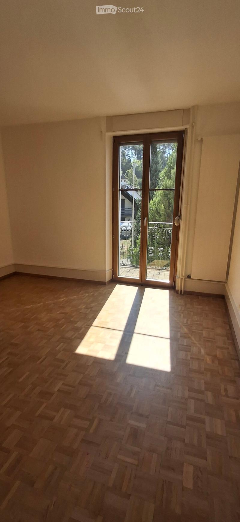 Empty room with wooden flooring and large sliding glass doors leading to a balcony or outdoor area.