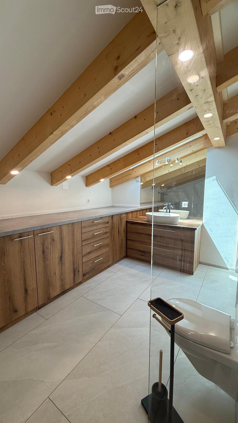 Modern bathroom with wooden cabinets, a large sink, a bathtub, and a glass partition separating the shower area.