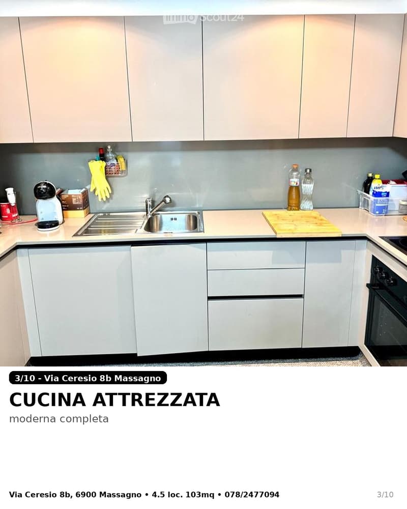 Modern kitchen with light-colored cabinets, stainless steel sink, oven, and various appliances and items on the counter.