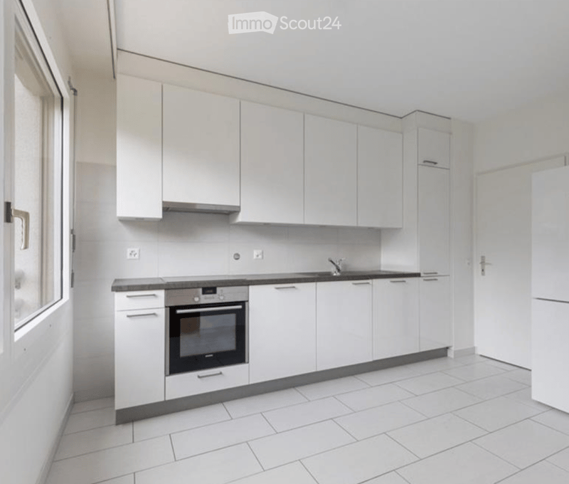 Modern kitchen with white cabinets, tiled floor, built-in oven, and sink.