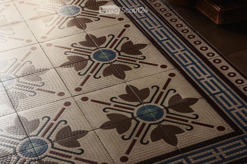 Ornate mosaic tile floor with floral and geometric patterns in shades of beige, brown, and blue.