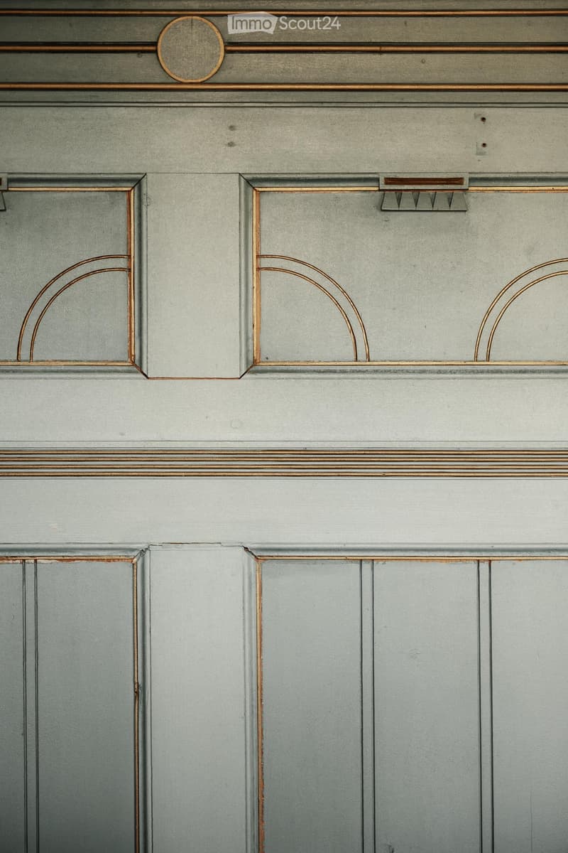 Close-up of a hallway with grey walls and decorative wooden trim featuring arched designs and a circular medallion above the door frame.