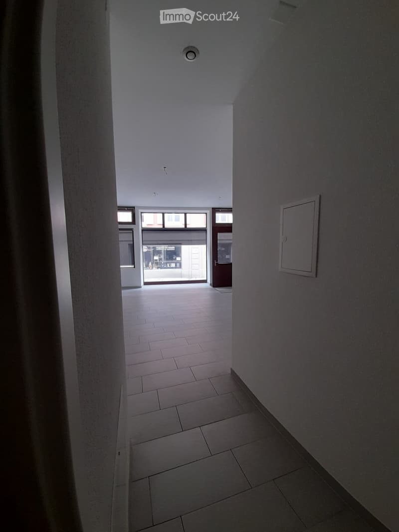 Empty hallway with tiled floor, white walls, and a door leading to an exterior area.