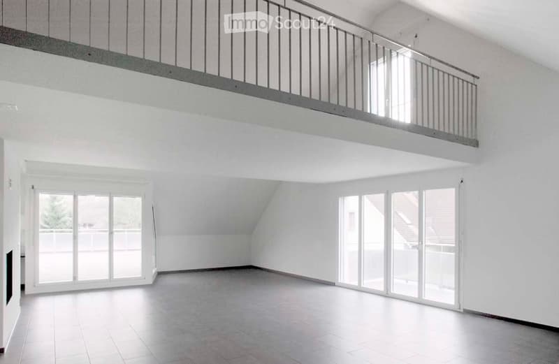 Empty room with white walls, tiled floor, large windows, and a balcony overlooking the space.