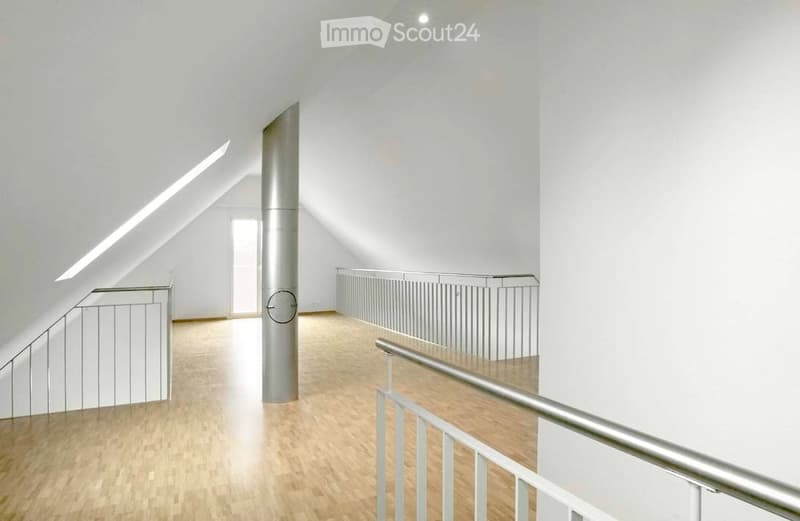 Bright, minimalist hallway with wooden flooring, white walls, and modern metal railings leading to an open space.