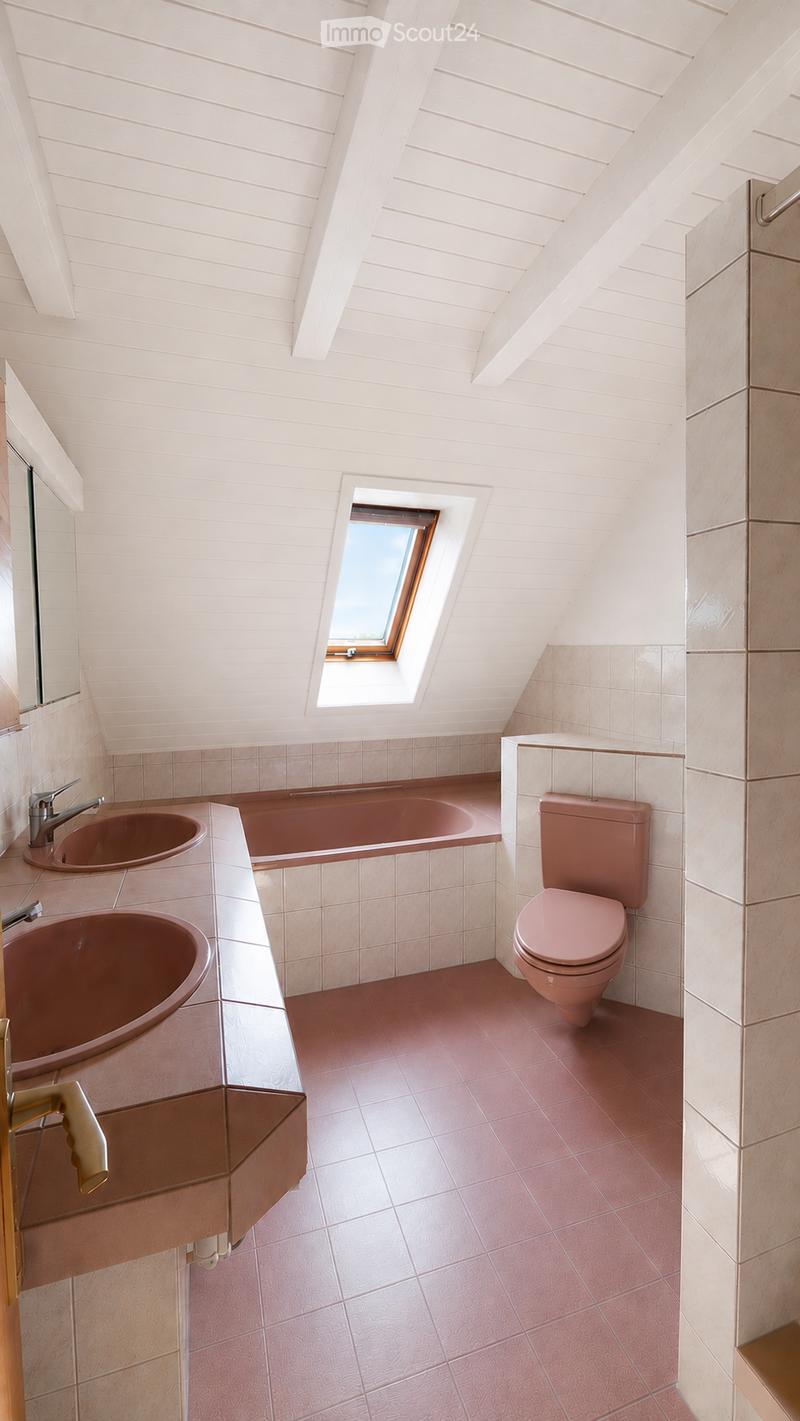 Modern bathroom with pink tiles, a bathtub, two sinks, a toilet, and a skylight window.