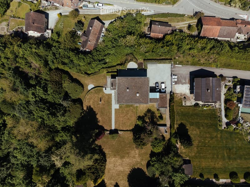 Aerial view of a residential complex with multiple buildings, parking areas, and surrounding greenery.