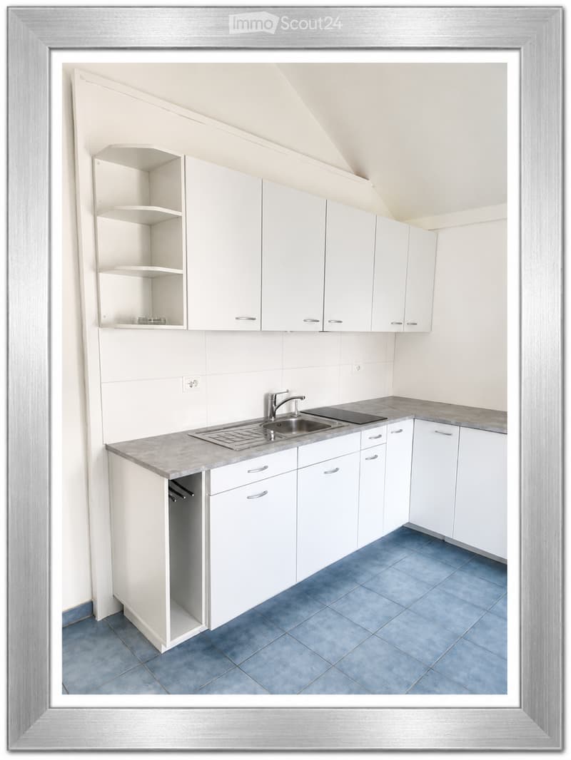 Modern kitchen with white cabinets, a stainless steel sink, and a gray countertop, featuring blue tiled flooring.