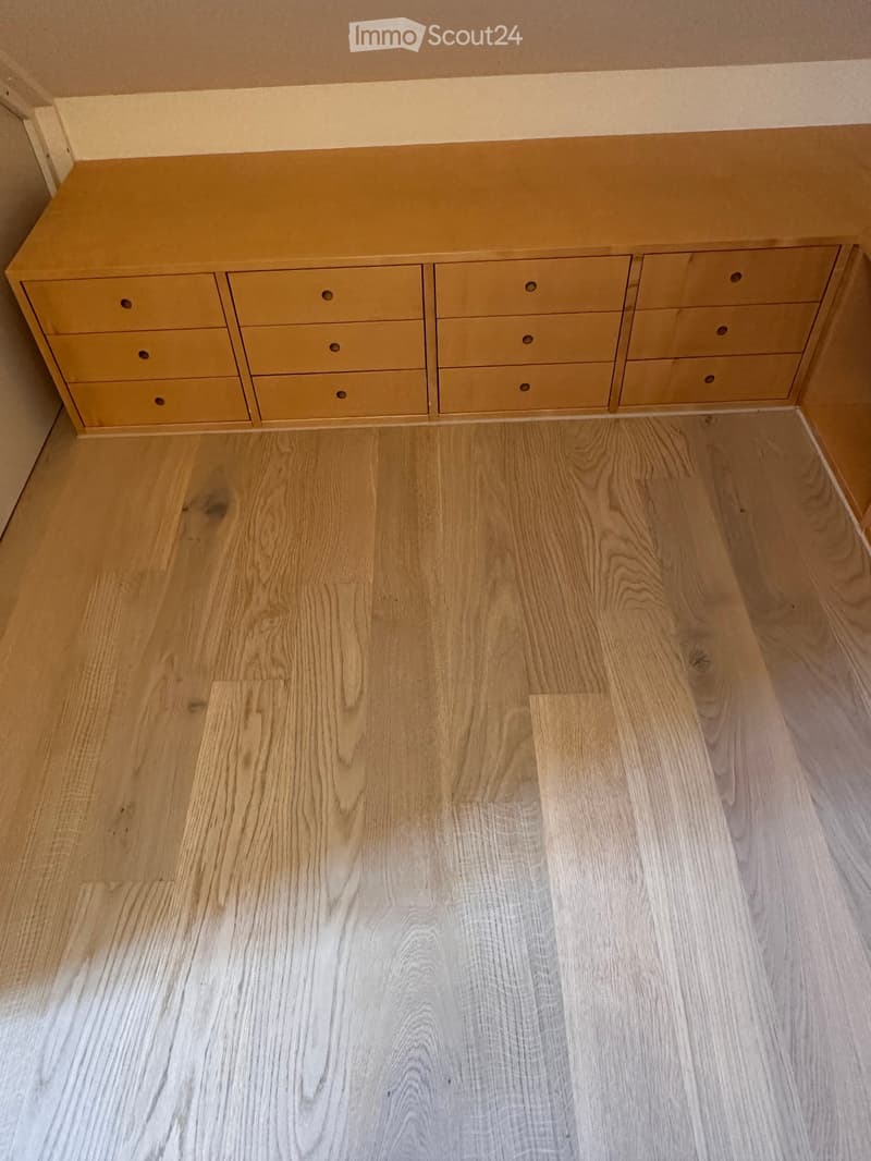 Empty room with light wooden flooring and a built-in yellow cabinet with multiple drawers.