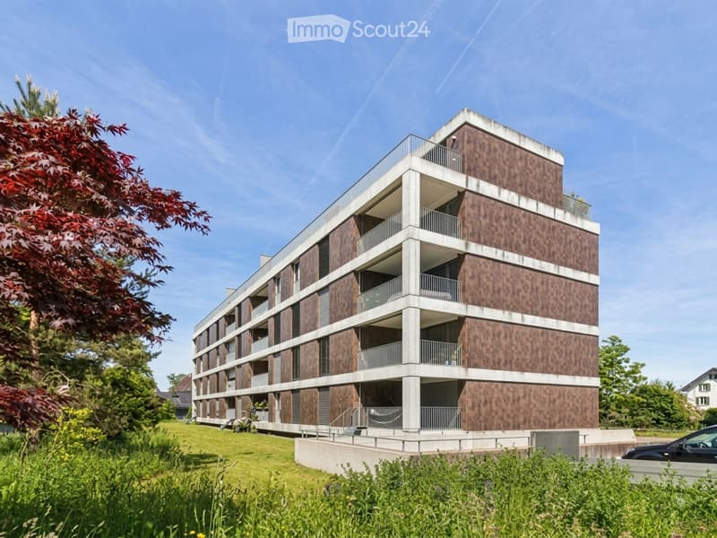 Modern multi-story residential building with a combination of wood and concrete facade, featuring multiple balconies and large windows.