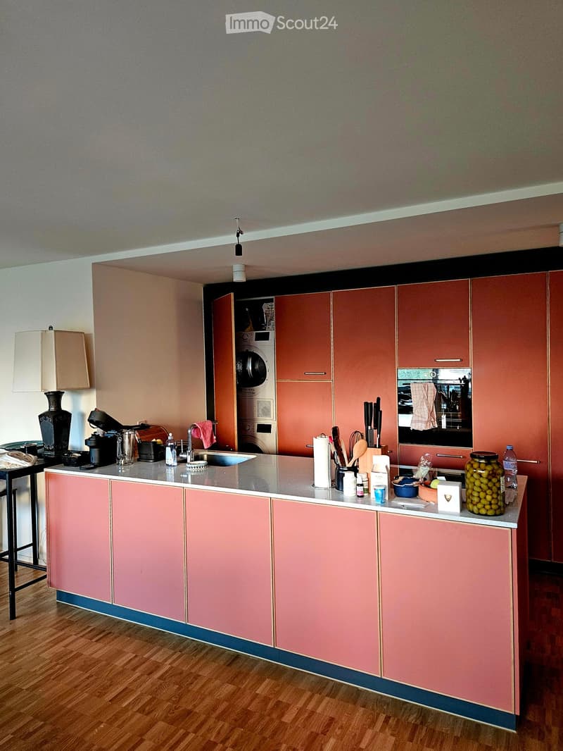 Modern kitchen with pink cabinets, a central island, and various appliances and items on the counter.