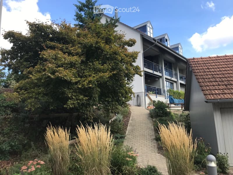 Modern two-story house with white exterior, multiple balconies, and a well-maintained garden with a brick pathway.