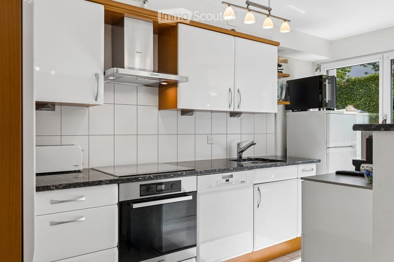 Modern kitchen with white cabinets, stainless steel appliances, granite countertops, and a built-in oven and dishwasher.
